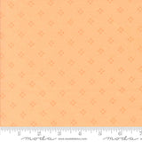 The image is a fabric with a repeating pattern of small orange dots or stars on a light orange background.