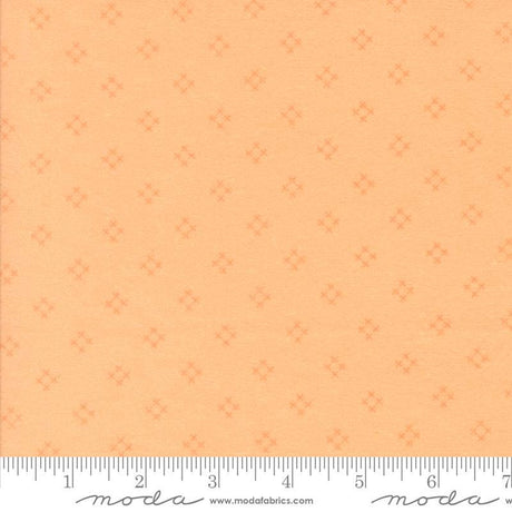 The image is a fabric with a repeating pattern of small orange dots or stars on a light orange background.