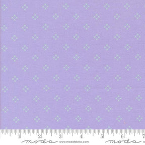 The image is a fabric with a purple background and a repeating pattern of small white stars or diamonds. The fabric appears to be a type of textile, possibly used for clothing or home decor.