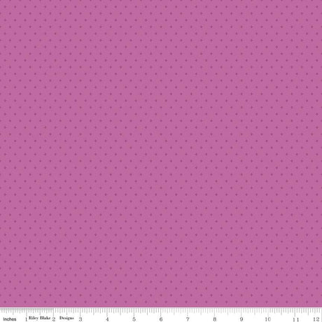 The image is a close-up of a fabric with a pink background and small white dots, resembling a polka dot pattern.