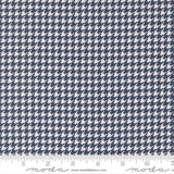 a close-up view of a fabric with a repeating pattern of white and navy blue houndstooth shapes.