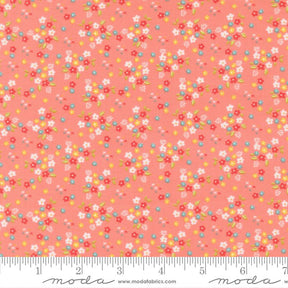 The image is a fabric with a floral pattern in shades of pink and orange. The pattern consists of small flowers and leaves scattered across the fabric, creating a vibrant and colorful design.