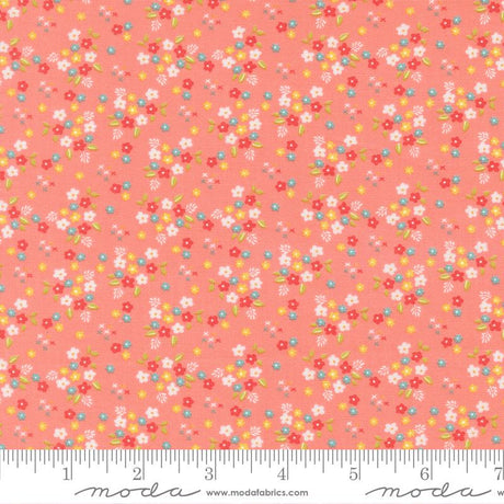 The image is a fabric with a floral pattern in shades of pink and orange. The pattern consists of small flowers and leaves scattered across the fabric, creating a vibrant and colorful design.