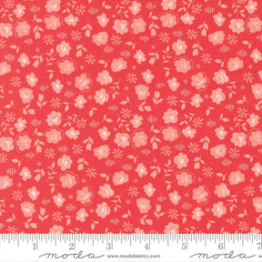 The image is a close-up of a fabric with a repeating pattern of pink flowers and leaves on a red background.