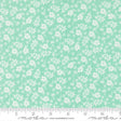 a fabric with a light green floral pattern, consisting of white flowers scattered across the fabric. The fabric is laid out on a ruler for size comparison.