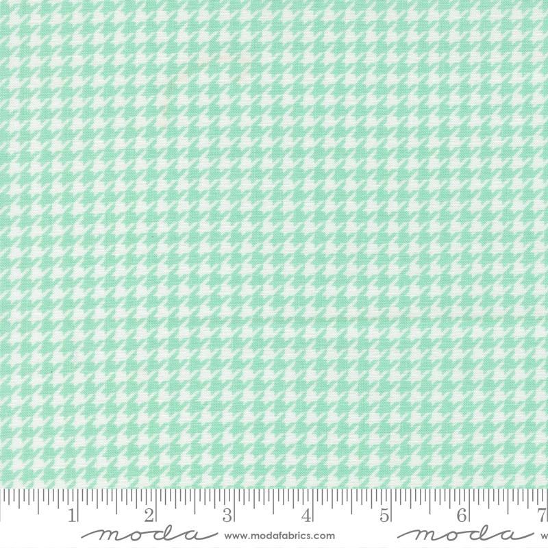 a fabric with a repeating pattern of green and white houndstooth shapes, creating a houndstooth pattern.