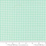 a fabric with a repeating pattern of green and white houndstooth shapes, creating a houndstooth pattern.
