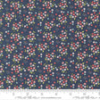 The image is a close-up of a fabric with a floral pattern, featuring small flowers in various colors and sizes against a dark blue background.