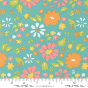 The image is a fabric with a floral pattern in shades of green, orange, and pink. The pattern consists of various flowers and leaves in different sizes and orientations, creating a vibrant and lively design.