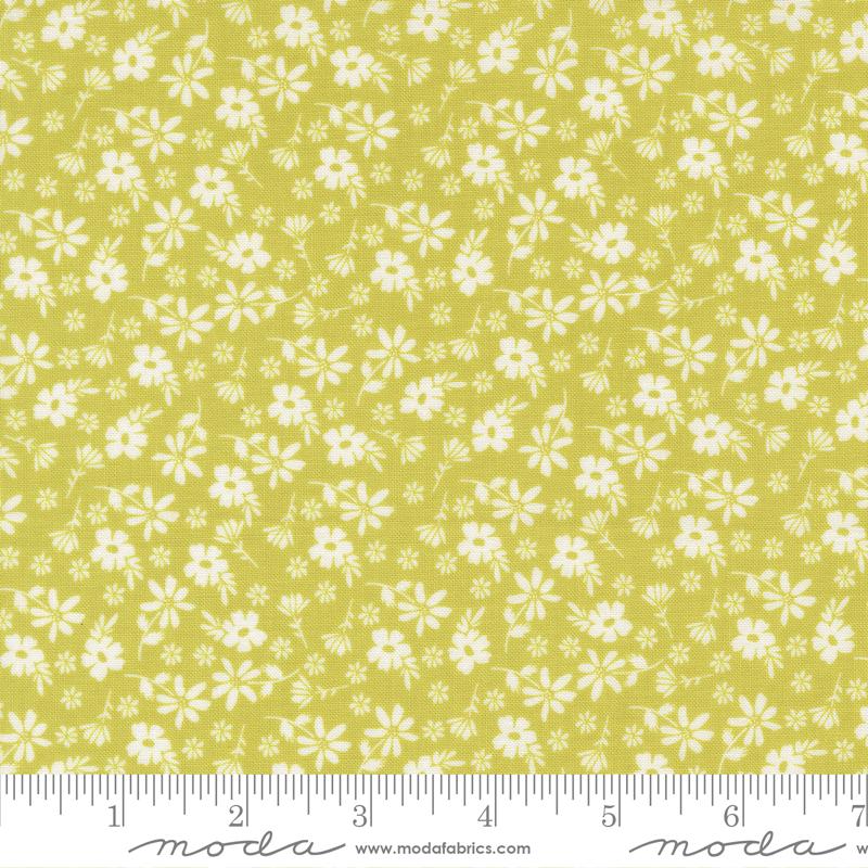 a fabric with a repeating pattern of white flowers on a yellow background. The fabric appears to be a fabric with a floral print, and it is displayed on a ruler for size reference.