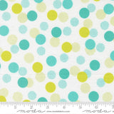 a white fabric with a pattern of multicolored polka dots in various shades of green, yellow, and blue. The fabric appears to be a textile or material with a playful and vibrant design.