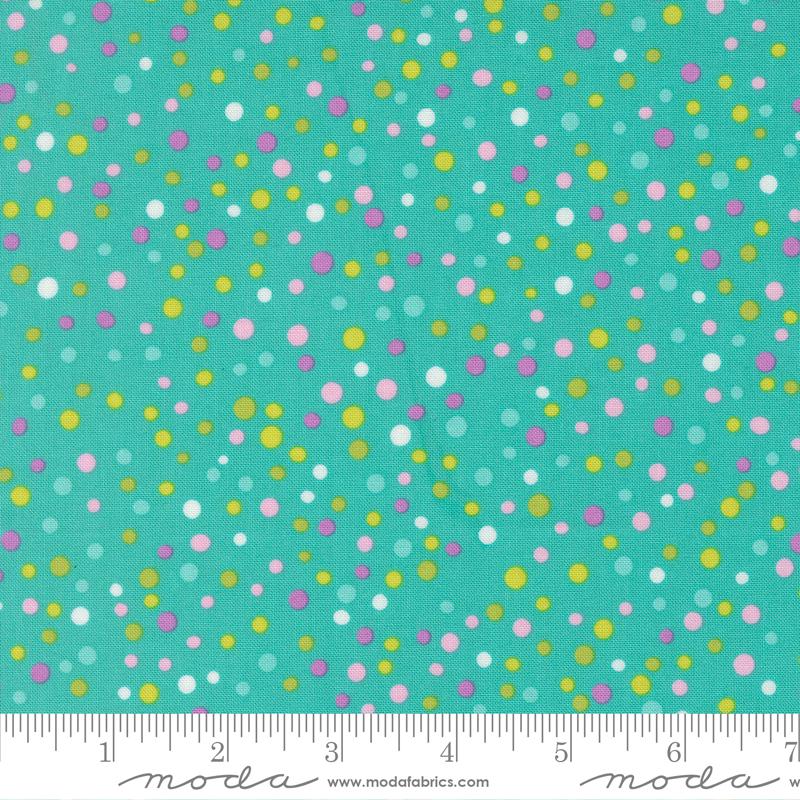 The image is a close-up of a fabric with a pattern of multicolored dots in various shades of green, yellow, and pink. The dots are scattered randomly across the fabric, creating a vibrant and lively visual effect.