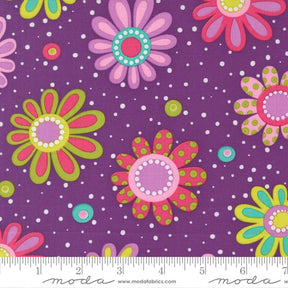 The image is a fabric with a purple background and colorful flowers with polka dots scattered throughout.