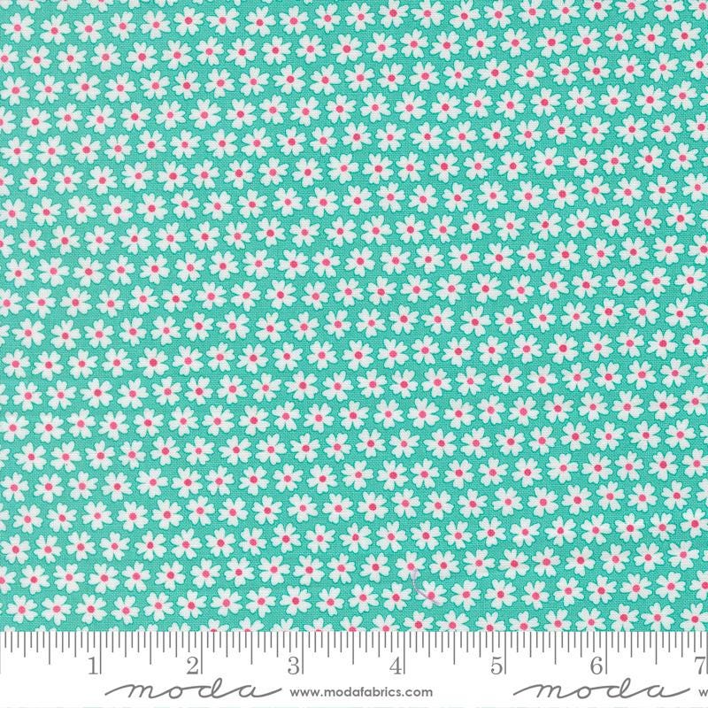 a fabric with a repeating pattern of white and pink flowers on a turquoise background. The fabric appears to be a textile or material with a floral design.