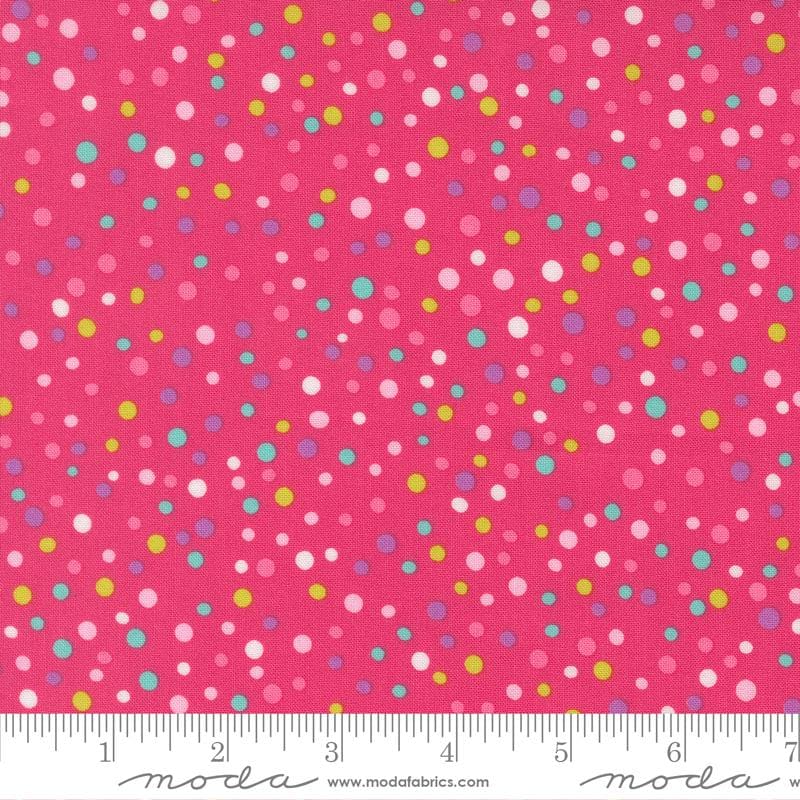 The image is a close-up of a fabric with a vibrant pink background adorned with multicolored polka dots in various sizes and shades.