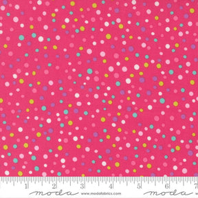 The image is a close-up of a fabric with a vibrant pink background adorned with multicolored polka dots in various sizes and shades.