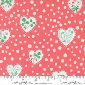a fabric with a pink background and white polka dots. It has a repeating pattern of hearts and leaves, as well as flowers and berries. The fabric appears to be a fabric with a floral pattern, possibly made of cotton.