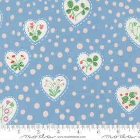 The image is a fabric with a blue background and white polka dots. It features heart-shaped designs with flowers and leaves, as well as other heart-shaped designs with flowers and leaves.