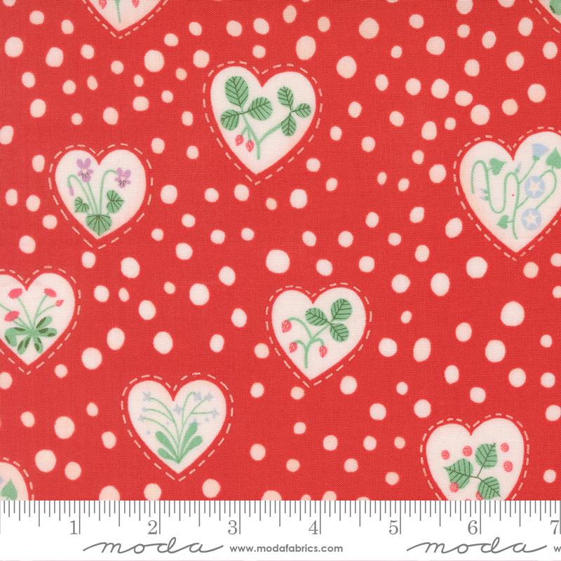 a red fabric with white polka dots and heart-shaped cutouts containing various floral designs, such as flowers and leaves.