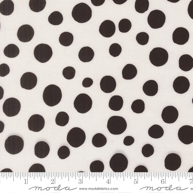 a close-up view of a fabric with a black and white polka dot pattern. The fabric is white with numerous black polka dots scattered across it. There is a ruler placed at the bottom of the image, indicating the size of the fabric.