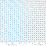 The image is a fabric with a repeating pattern of small blue flowers or leaves. The pattern is evenly spaced and covers the entire fabric. The fabric appears to be made of a light-colored material, possibly cotton or linen. The image does not contain any text or other objects, and the focus is solely on the pattern and color of the fabric.