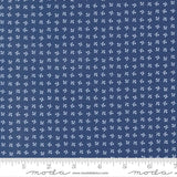 The image is a close-up of a fabric with a repeating pattern of small white flowers or leaves. The fabric appears to be navy blue in color.