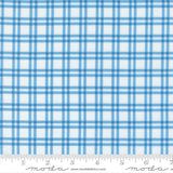 a fabric with a blue and white checkered pattern. The fabric appears to be a type of plaid or gingham, with a grid-like design. The fabric is displayed on a ruler for scale, indicating its size.