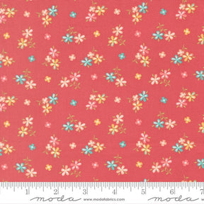 a vibrant red fabric with a repeating pattern of small, colorful flowers in shades of pink, blue, and yellow. The flowers are scattered across the fabric in a random yet visually appealing manner, creating a lively and cheerful design.