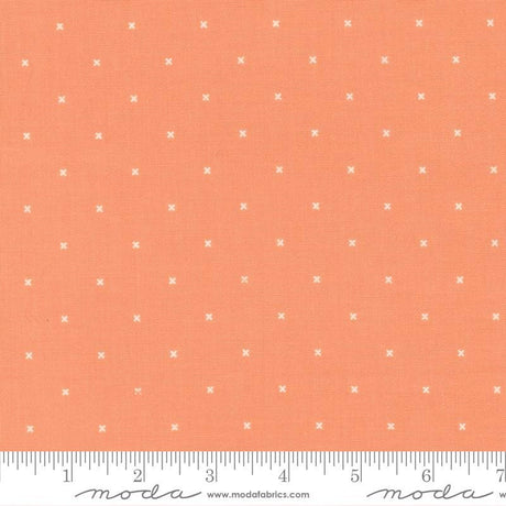 The image is a fabric with a repeating pattern of small white crosses or dots on an orange background.