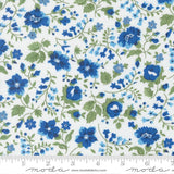 The image is a close-up of a fabric with a floral pattern in shades of blue and green. The pattern consists of various blue flowers and green leaves arranged in a repeating design. The fabric appears to be a white material with the floral pattern printed on it.