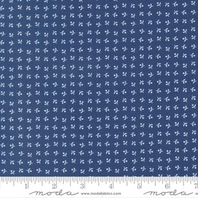 The image is a close-up of a fabric with a repeating pattern of small white flowers or leaves. The fabric appears to be navy blue in color.