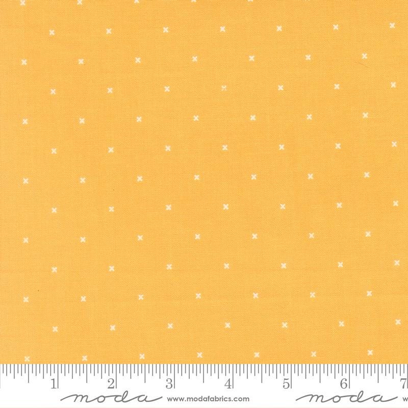 The image is a fabric with a yellow background and white dotted pattern.
