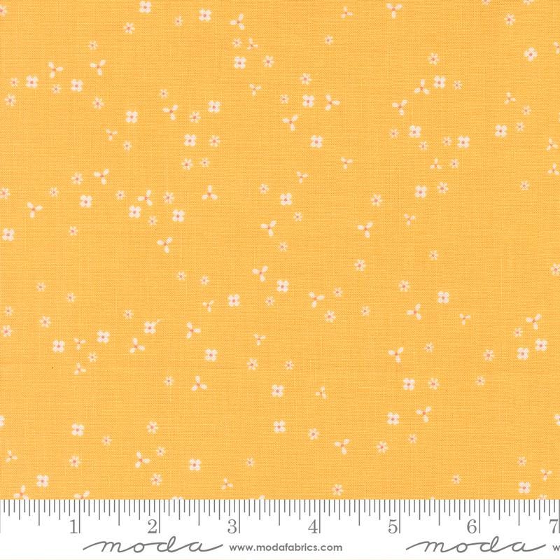The image is a fabric with a yellow background and small white flowers scattered across it.