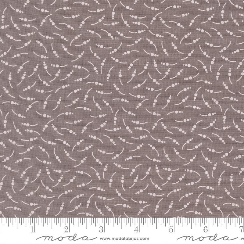 The image is a fabric with a repeating pattern of small white dots or circles on a brown background.