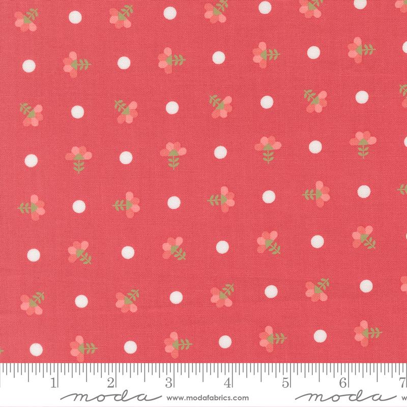 a red fabric with white polka dots and small green flowers printed on it. The fabric appears to be a part of a larger textile or garment, as indicated by the ruler for scale.