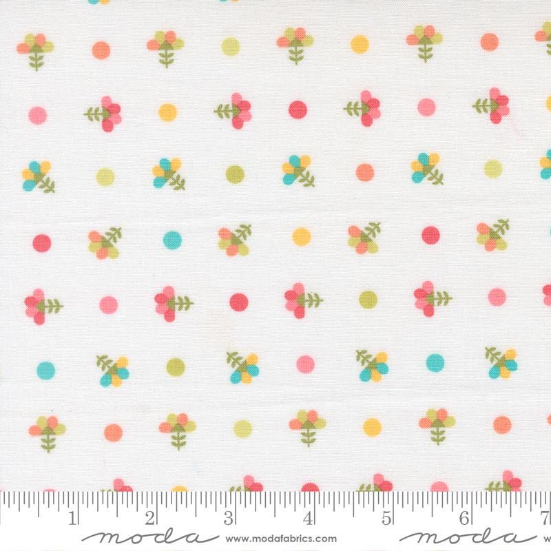 The image is a fabric with a repeating pattern of colorful flowers and polka dots.