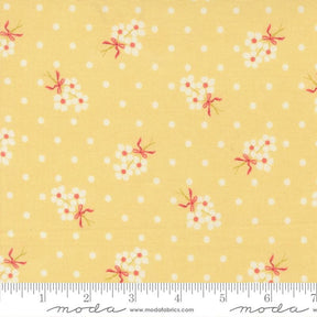 The image is a fabric with a yellow background and white polka dots, featuring small white flowers with pink bows.