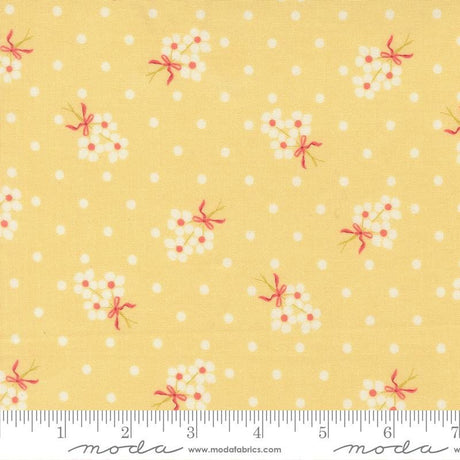 The image is a fabric with a yellow background and white polka dots, featuring small white flowers with pink bows.