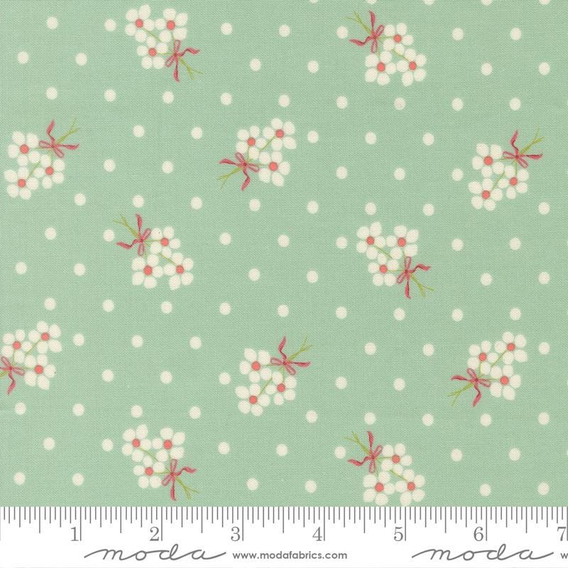 a fabric with a repeating pattern of white flowers with red bows against a light green background with white polka dots.