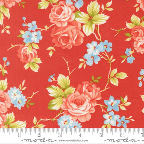 a vibrant red fabric adorned with a floral pattern of pink roses and blue flowers. The fabric is displayed on a ruler for scale, indicating its size.