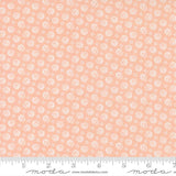 The image is a fabric with a repeating pattern of small white flowers or circles on a peach-colored background.