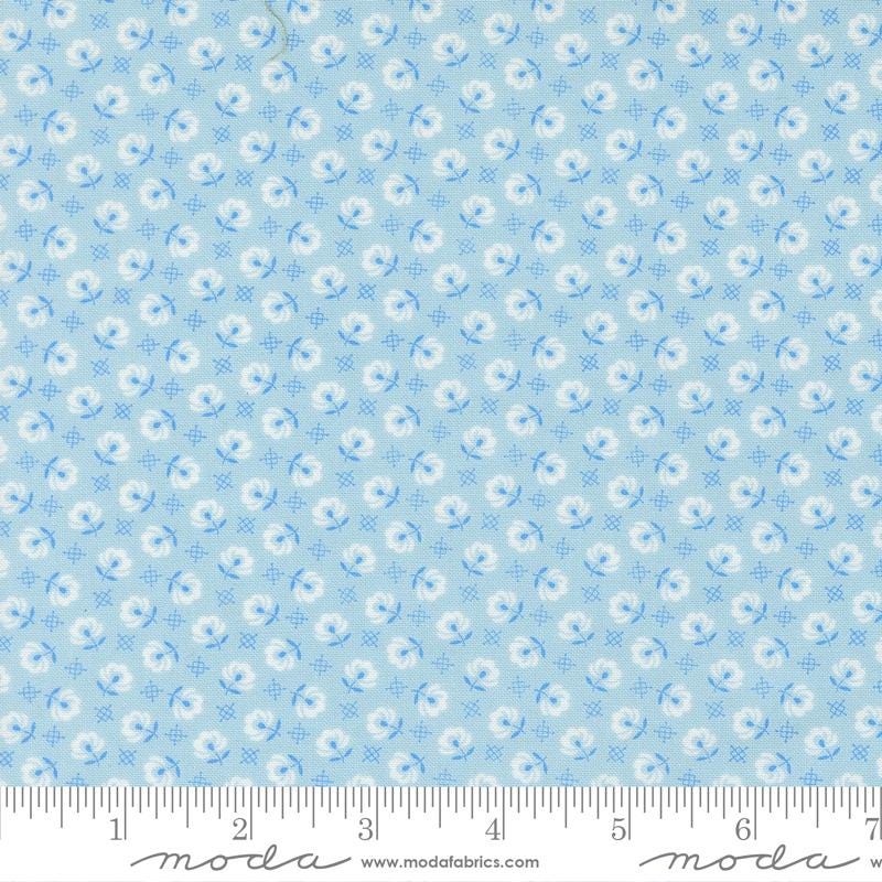 The image is a fabric with a repeating pattern of blue flowers and white flowers. The pattern is composed of small blue flowers and white flowers arranged in a grid-like fashion. The fabric appears to be light blue in color.