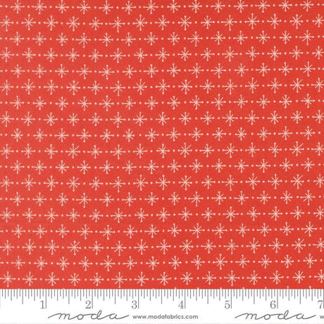 a red fabric with a repeating pattern of white snowflakes. The fabric has a ruler at the bottom to provide a scale for the image.