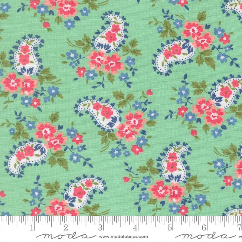 The image is a fabric with a paisley pattern in shades of green, pink, and blue. The pattern consists of various paisley designs and floral elements, creating a vibrant and visually appealing design.