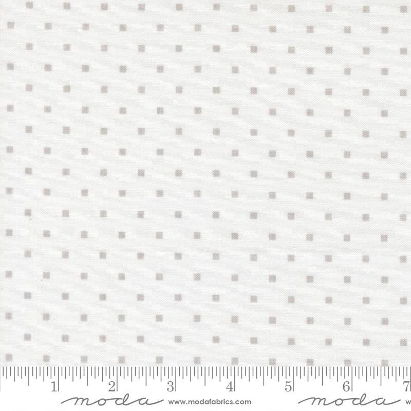 The image is a fabric with a grey dotted pattern, and it is being measured for size.