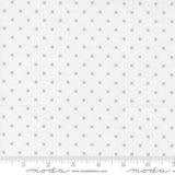 The image is a fabric with a grey dotted pattern, and it is being measured for size.
