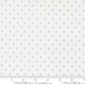 The image is a fabric with a grey dotted pattern, and it is being measured for size.