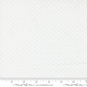 The image is a white fabric with a repeating pattern of small white flowers or leaves. The fabric appears to be a type of lace or sheer material, as it has a delicate and intricate design. The fabric is displayed on a ruler for scale, indicating its size.