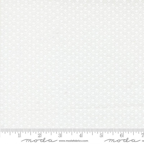 The image is a white fabric with a repeating pattern of small white flowers or leaves. The fabric appears to be a type of lace or sheer material, as it has a delicate and intricate design. The fabric is displayed on a ruler for scale, indicating its size.
