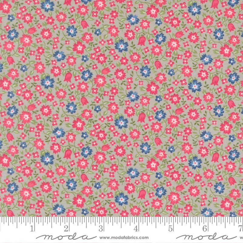 The image is a fabric with a floral pattern in shades of pink, blue, and green. The pattern consists of small flowers and leaves scattered across the fabric, creating a visually appealing and colorful design.